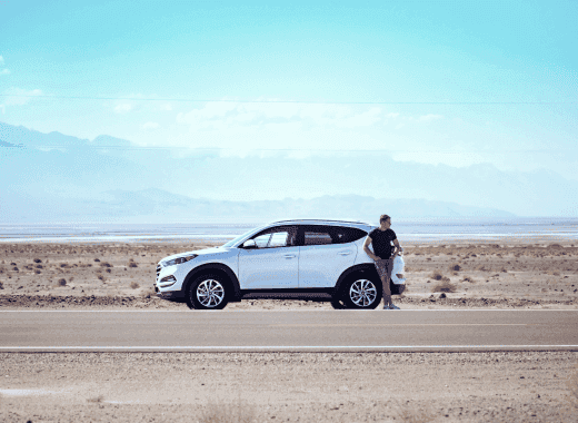 image of a man leaning on the outside of his car in the desert